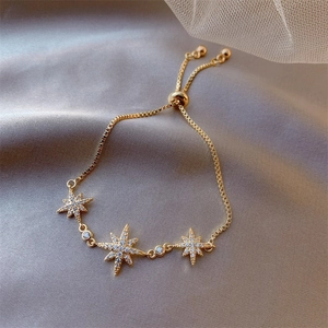 Detailed view of adjustable gold star bracelet with inlaid crystals on grey silk