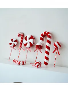 Close-up of red and white candy cane ornaments with glitter texture on a white mantle