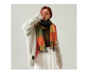 Detail showing multi-color plaid scarf with tassels on grey sweater and white pants