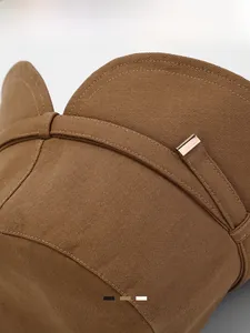 Detailed macro view of brown cotton sun hat featuring decorative strap and metal buckle