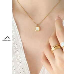 Détail d'un pendentif en nacre blanche carrée sur un collier en acier inoxydable doré 18k