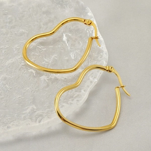 Boucles d'oreilles cœur dorées polies aux contours minimalistes sur fond texturé