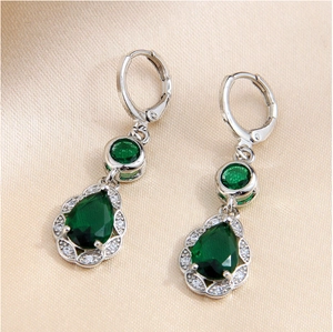 Elegant silver earrings with teardrop green zircon and white diamonds on silk background