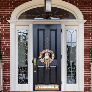 Christmas wreath with gnome doll and Welcome wooden sign hanging on a black front door