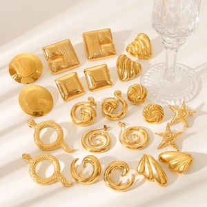 Close-up of gold stainless steel earrings featuring heart and geometric shapes on glass