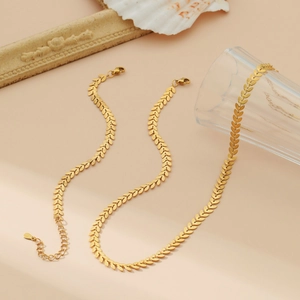 Elegant 18k gold wheat leaf necklace and bracelet set shown in a minimalist warm setting