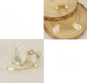 Detail of elegant gold drop earrings with white pearls and minimalist metal chains