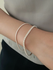 Close-up of thin and thick 925 silver tennis bracelets with zircon stones worn together