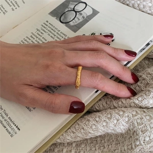Detail of a gold knotted knot ring with spiral texture worn on finger in a warm setting