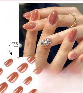 Detail of almond-shaped brick red press-on nails with silver glitter and dense rhinestones