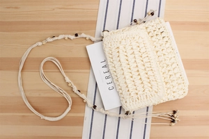 Detail of hand-woven cream shoulder bag with stylish wooden bead decorative strap
