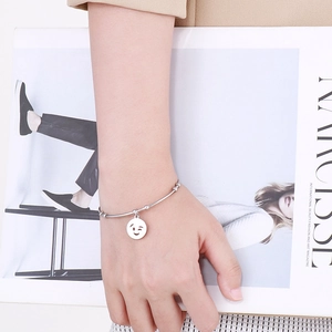 Titanium steel bracelet with silver winking emoji pendant worn on a model's wrist