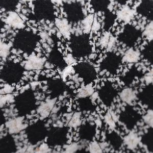 Makrodetail von schwarz-weißem Plaid-Tweed-Stoff mit dezenten Goldfaden-Akzenten