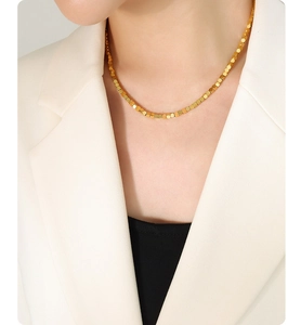 Close-up of minimalist gold square bead necklace layered over a white blazer