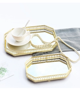 Detailed view of two octagonal gold mirror trays with hollow metal patterned edges