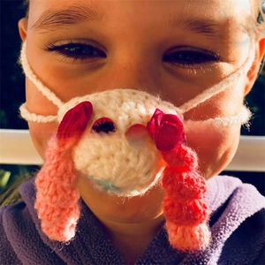 Close-up of handmade sheep-shaped nose warmer with red ribbons and soft wool texture