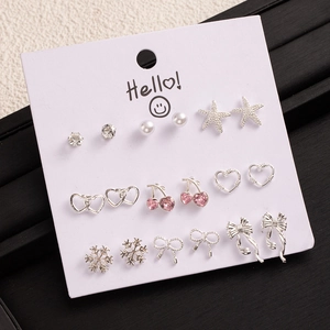 Macro view of a 9-pair silver stud earring set with cherry, heart, and pearl details