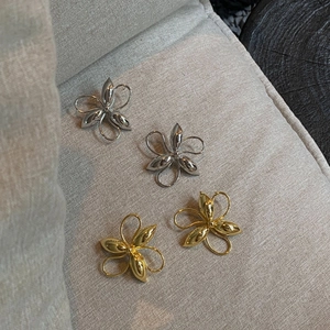 Detailed top view of gold and silver flower stud earrings on textured fabric