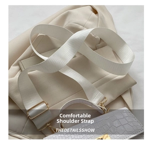 Detail of white nylon wide shoulder strap with gold metal buckle on faux crocodile bag