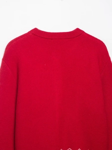 Détail de l'encolure ronde côtelée et de la texture en maille fine du gilet rouge