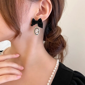 Detail of velvet bow earrings with pearl pendant shown on a model in vintage style