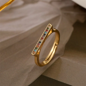 Detalle de anillo dorado ajustable con barra rectangular y circonitas de colores brillantes
