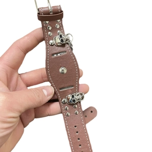 Brown leather punk watch strap with silver skull charms and metal rivets on white background