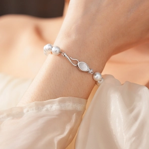 Detailed shot of a pearl bracelet with a shell-inlay clasp on a silk sleeve
