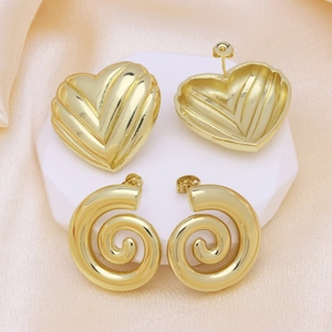 Golden heart relief and spiral screw stud earrings set on elegant white marble pedestal