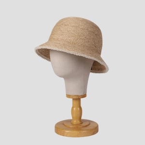 Elegant raffia straw cloche hat with frayed edges on a wooden display stand