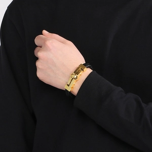 Detail view of the golden metal clasp on black braided leather bracelet for men