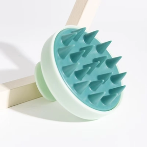 Manual scalp massage brush with green handle and soft teal silicone bristles for hair care