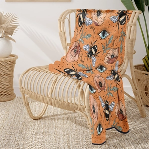 Detail of soft orange flannel blanket with vintage bee and poppy flower patterns