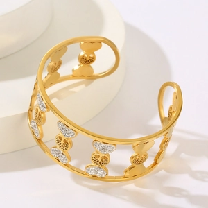 Macro detail of gold tree of life bangle featuring hollow design and heart-shaped crystals