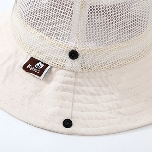 Dettaglio della maglia traspirante e dell'etichetta con logo orso sul cappello beige