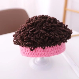 Dettaglio cappello neonato rosa a maglia con parrucca marrone all'uncinetto riccia in alto