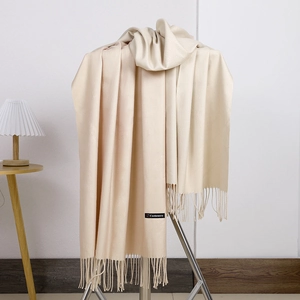 Close-up of beige cashmere scarf with tassels and authentic material tag detail