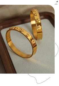 Detail shot of 18k gold plated stainless steel bangles with five-leaf flower engravings
