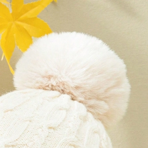 Schicke cremefarbene Strickmütze mit Zopfmuster und großem Pompon für warme Wintertage