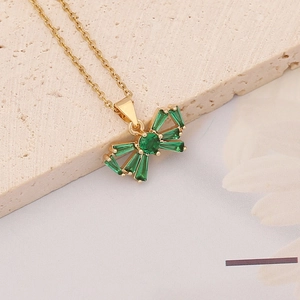 Close-up of golden bow pendant necklace with green emerald zircon inlays on stone