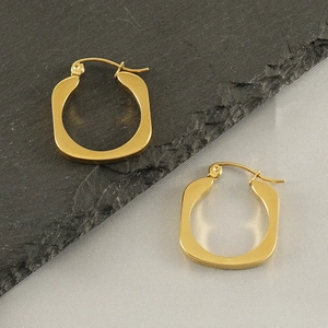 Detail of 18k gold-plated irregular geometric earrings on a minimalist slate background