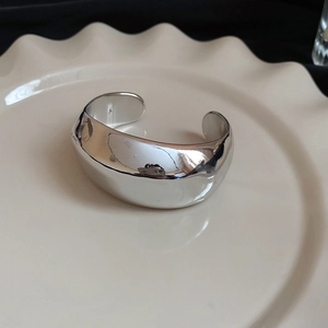 Dettaglio di un bracciale a polsino largo in argento lucido dal design unico