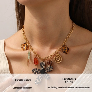 Détail du collier chaîne dorée avec fleur léopard et pendentifs variés en résine