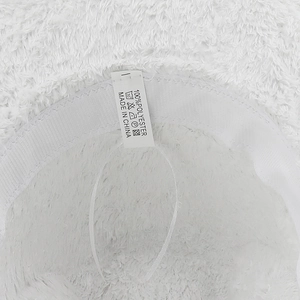 Détail de l'étiquette 100% polyester sur le chapeau de cowboy en peluche avec soins de lavage