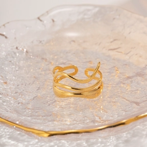 Makroaufnahme eines goldenen Wellenrings auf einem gehämmerten Glastablett