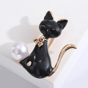 Detailed close-up of a black enamel cat brooch with a white pearl and gold accents
