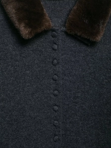Detail of dark grey knit jacket showing brown faux fur collar and covered buttons