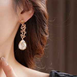 Close-up of champagne crystal teardrop earrings in gold plating on model