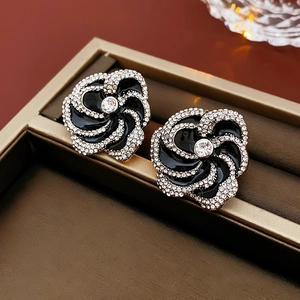 Detailed view of flower earrings with black enamel and clear rhinestones on a tray