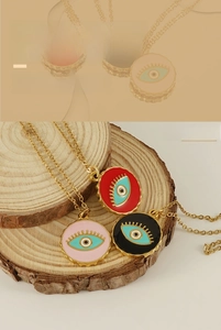 Detailed macro shot of three Evil Eye pendants in red, black and pink with gold chains